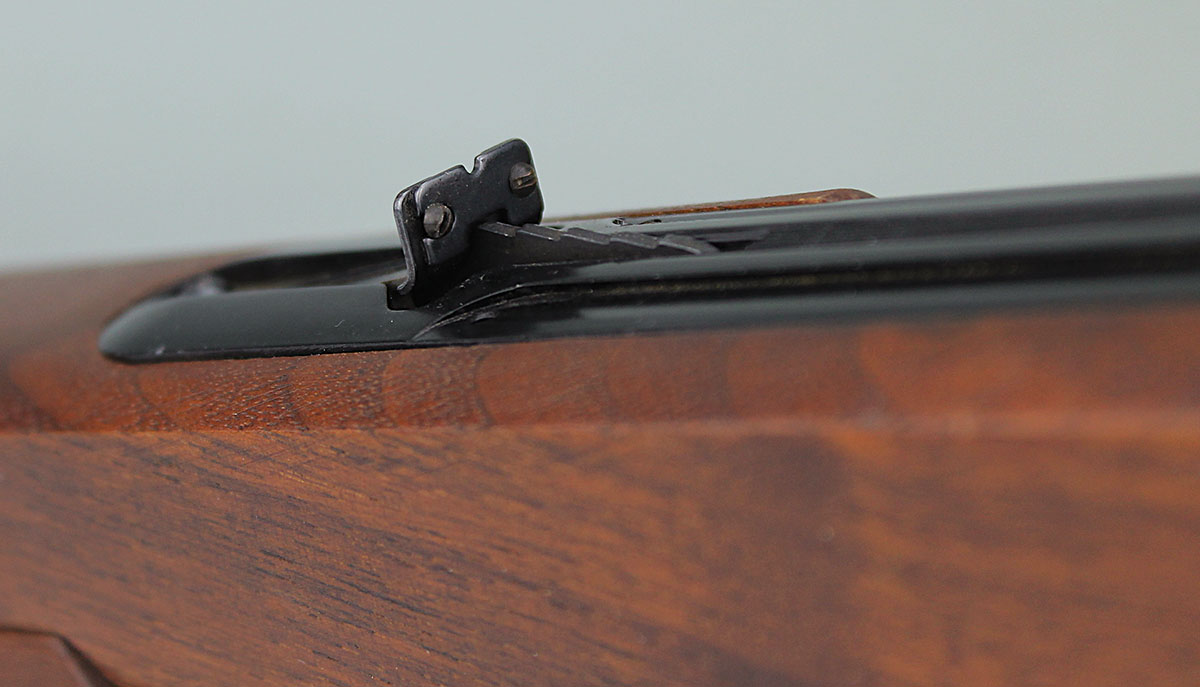 A simple rear sight with elevation adjustment is attached to the action cover plate.